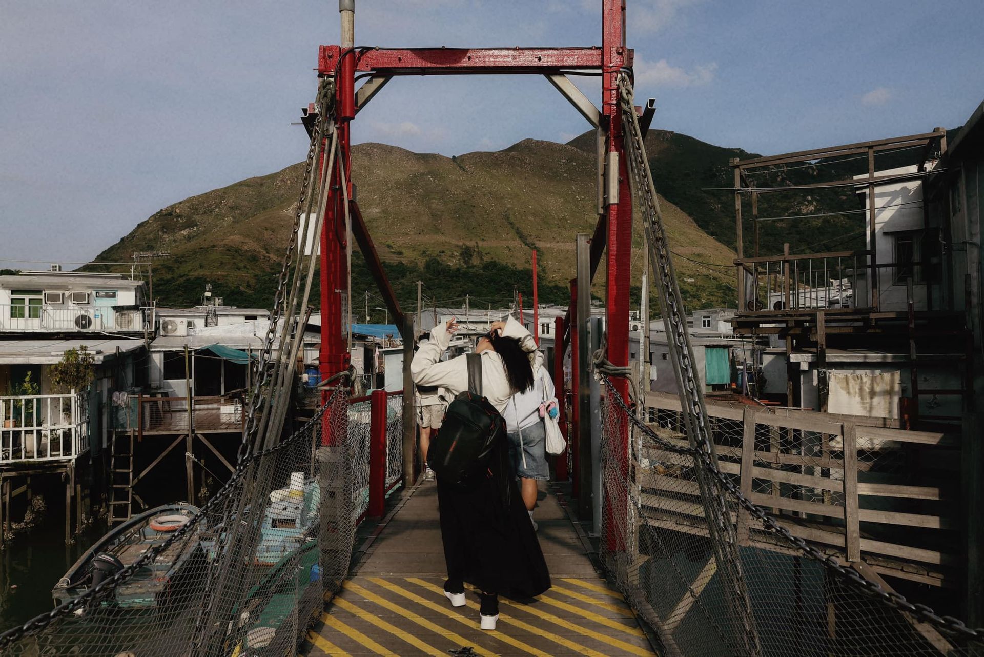 A woman is walking across a bridge in a tai o fishing village.