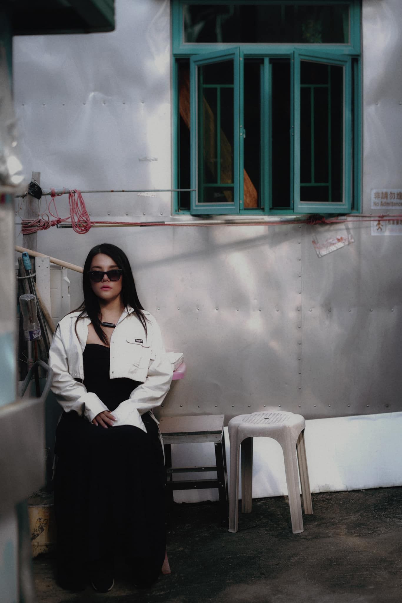 A woman wearing sunglasses is sitting in front of a window.