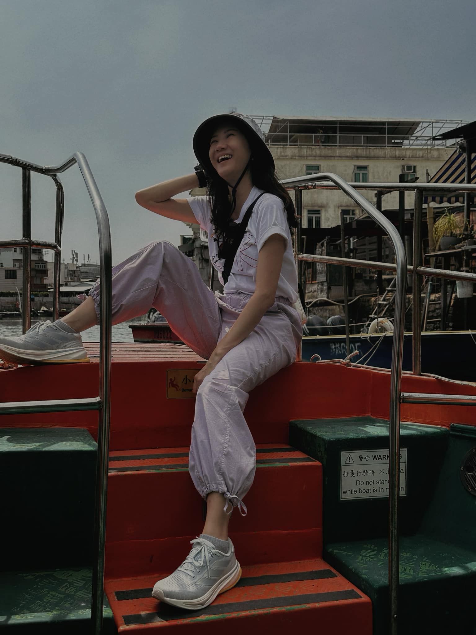 A woman is sitting on the stairs of a boat.