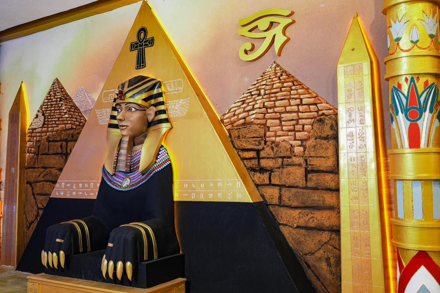 A statue of a sphinx sitting on a pyramid with pyramids in the background.