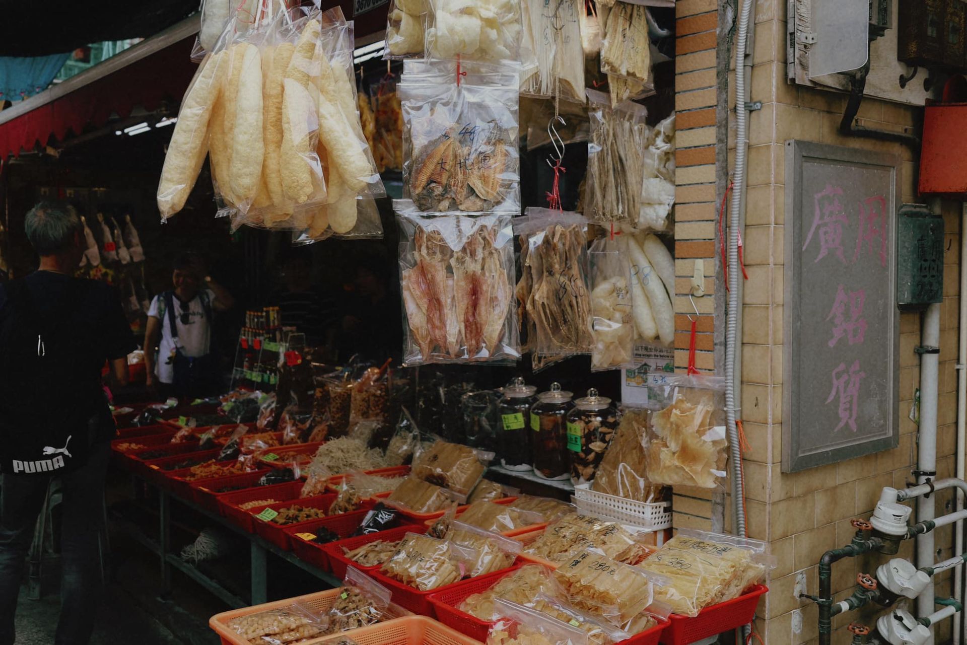 A man is standing in front of a store selling food.