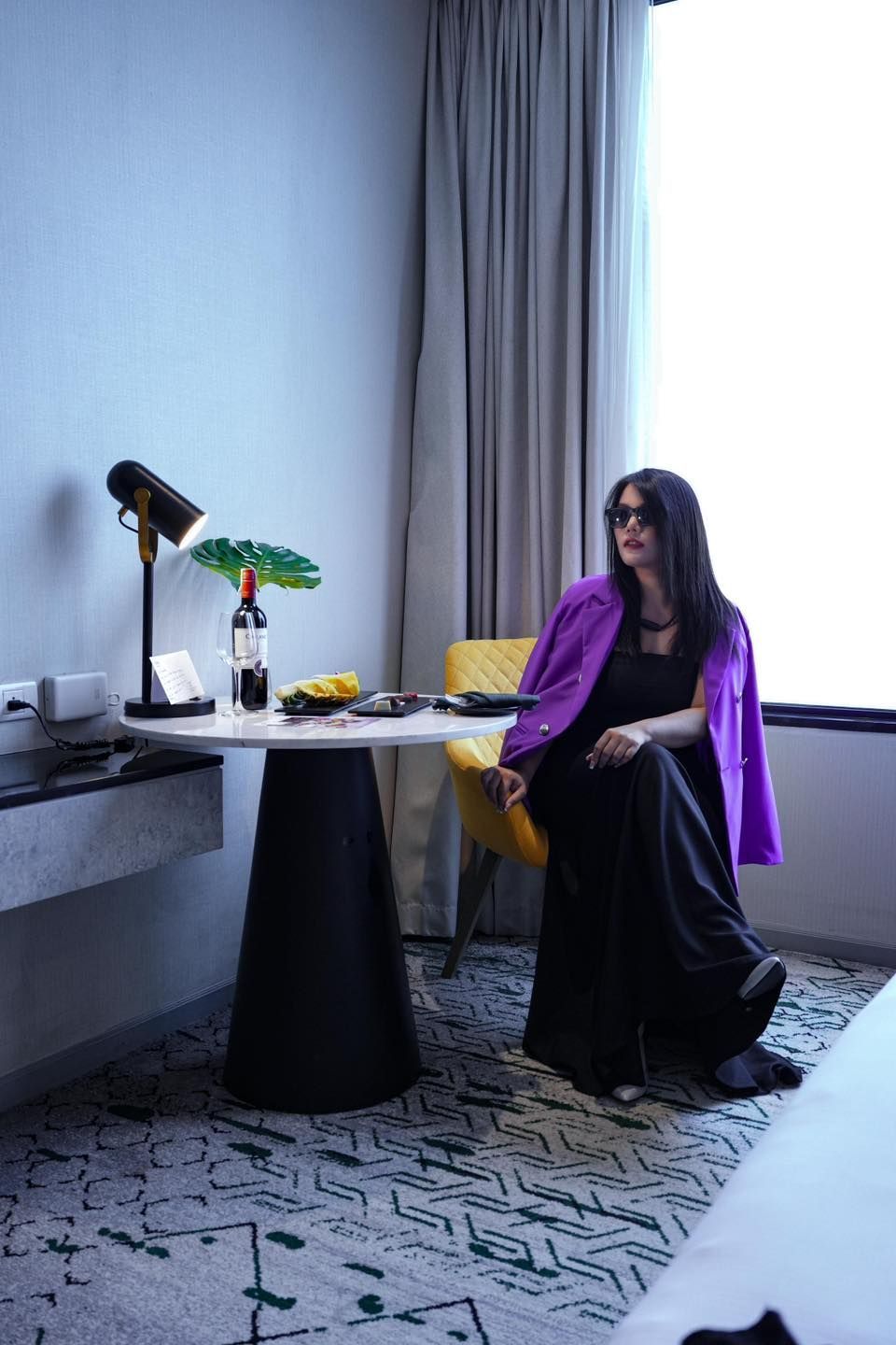 A woman in a purple jacket is sitting at a table in a  in Avani Sukhumvit Bangkok hotel room.