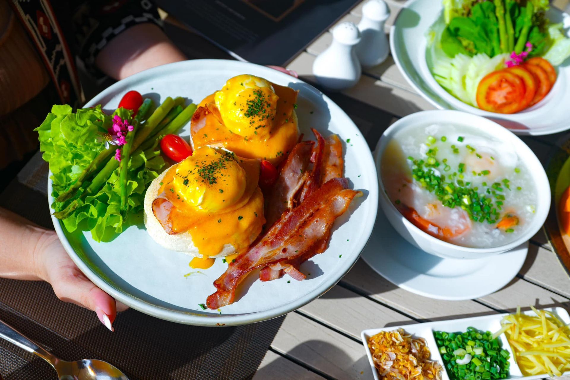 A person is holding a plate of food on a table.
