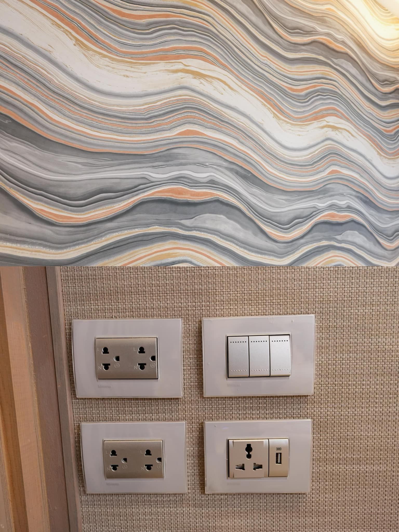A close up of a wall with a marble pattern and electrical outlets.