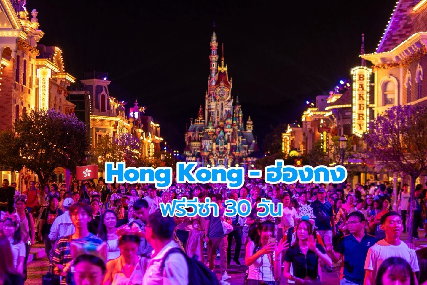 Hong Kong Disneyland at night, crowded with people. Illuminated buildings and castle, Thai text overlay.