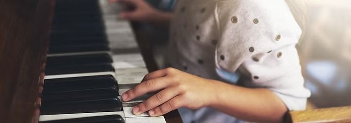 A person’s hands playing the keys of a piano.