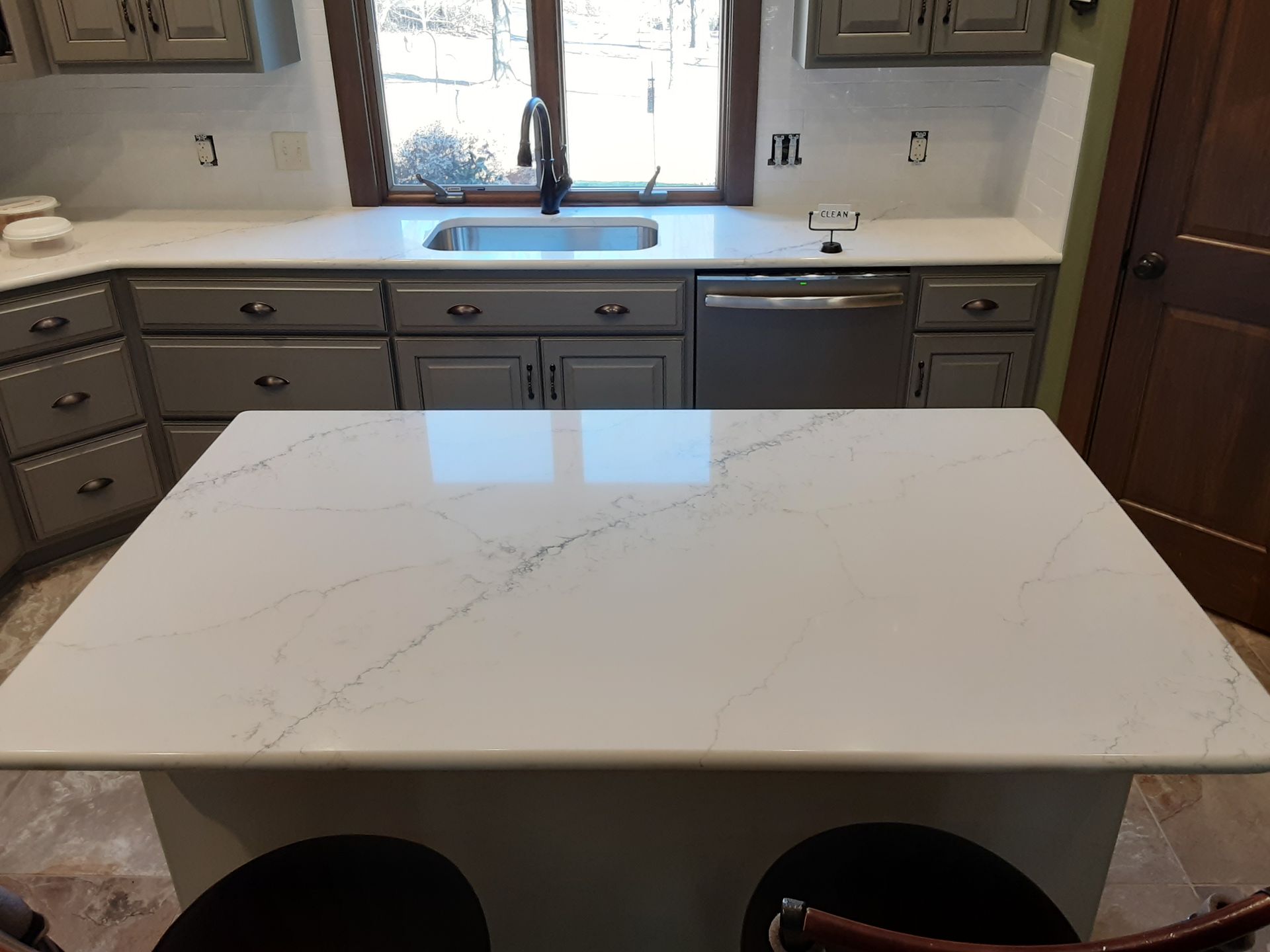 Kitchen with white countertops, gray cabinets, stainless steel appliances, and a central island with seating.