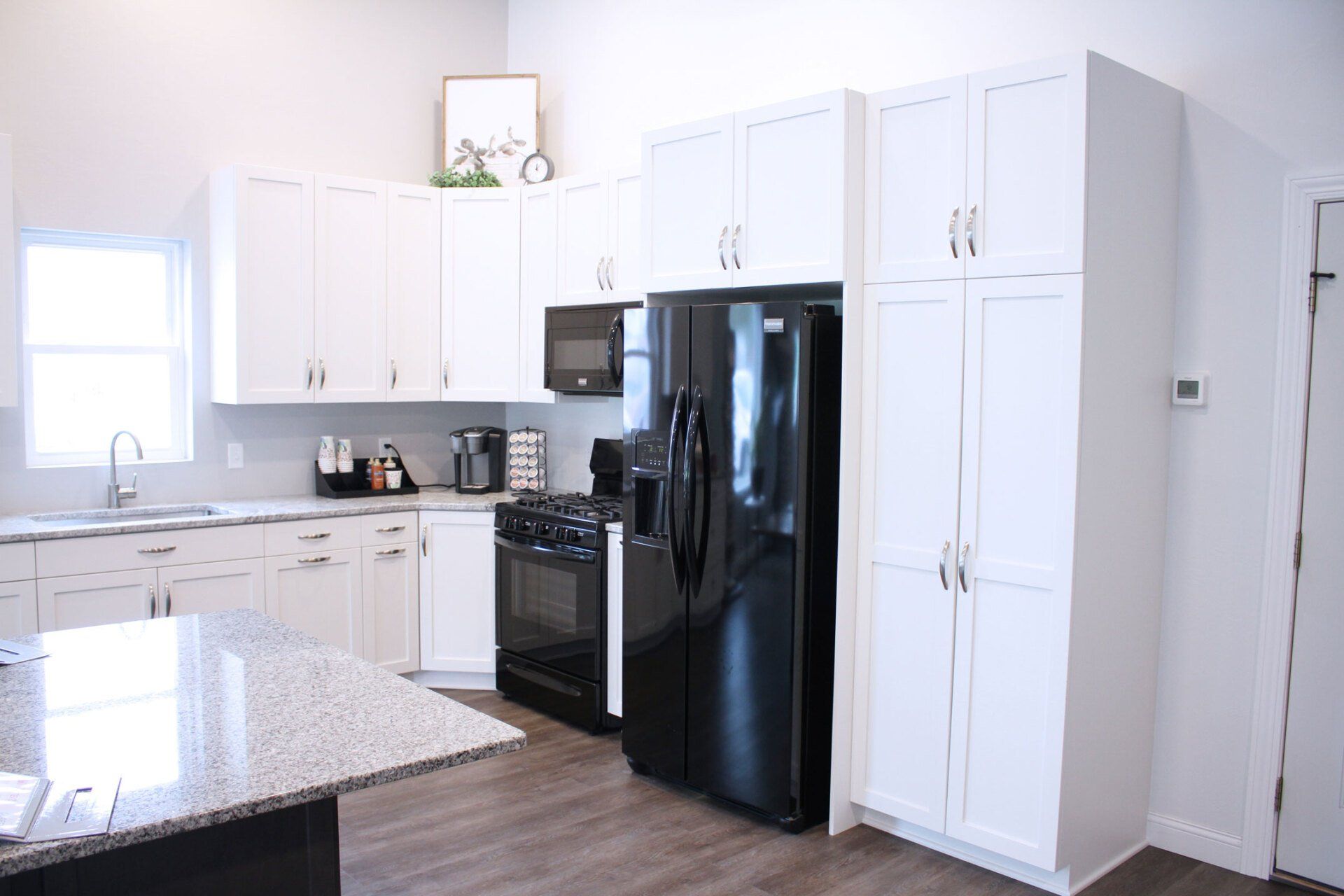 White kitchen with a black refrigerator, cabinets, and appliances.