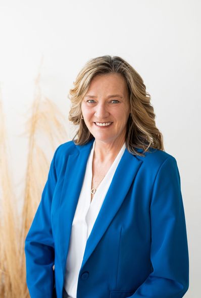 A woman in a blue jacket and white shirt is smiling for the camera. A woman in a blue jacket and white shirt is smiling for the camera.
