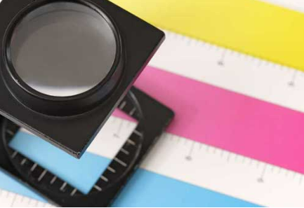 A magnifying glass is sitting on top of a colorful ruler A magnifying glass is sitting on top of a colorful ruler