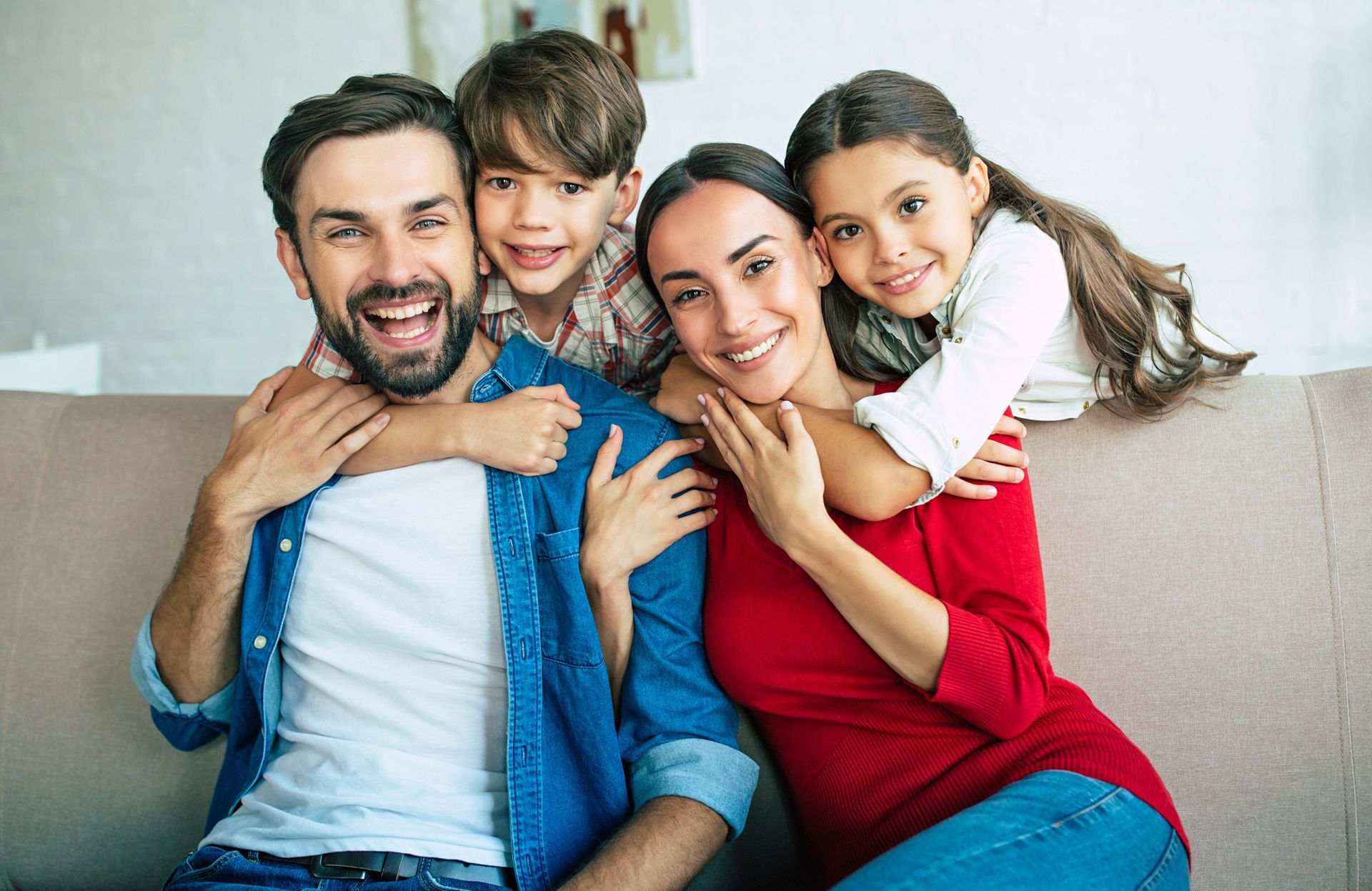 A family is posing for a picture while sitting on a couch.