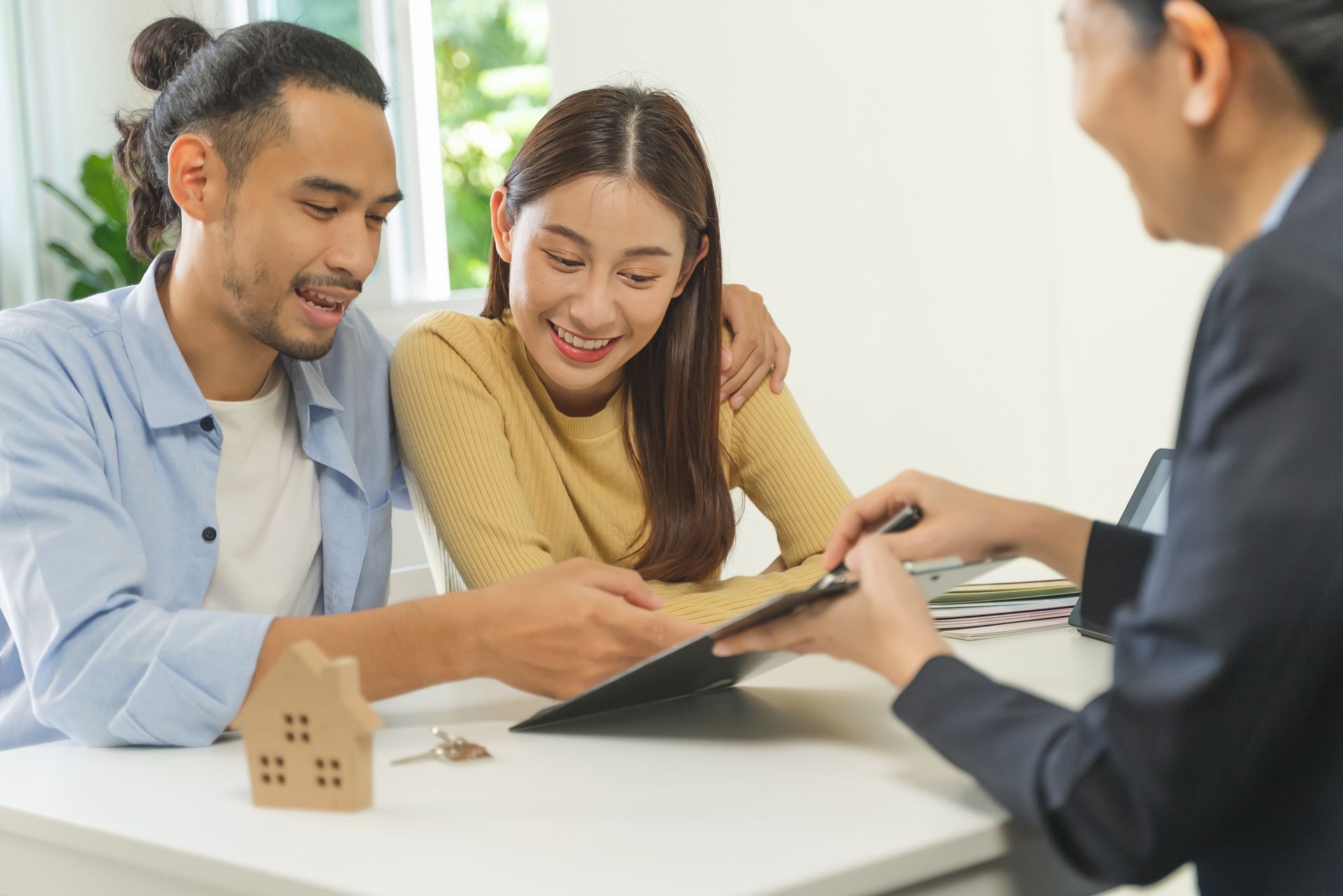 A man and woman are sitting at a table talking to a real estate agent.