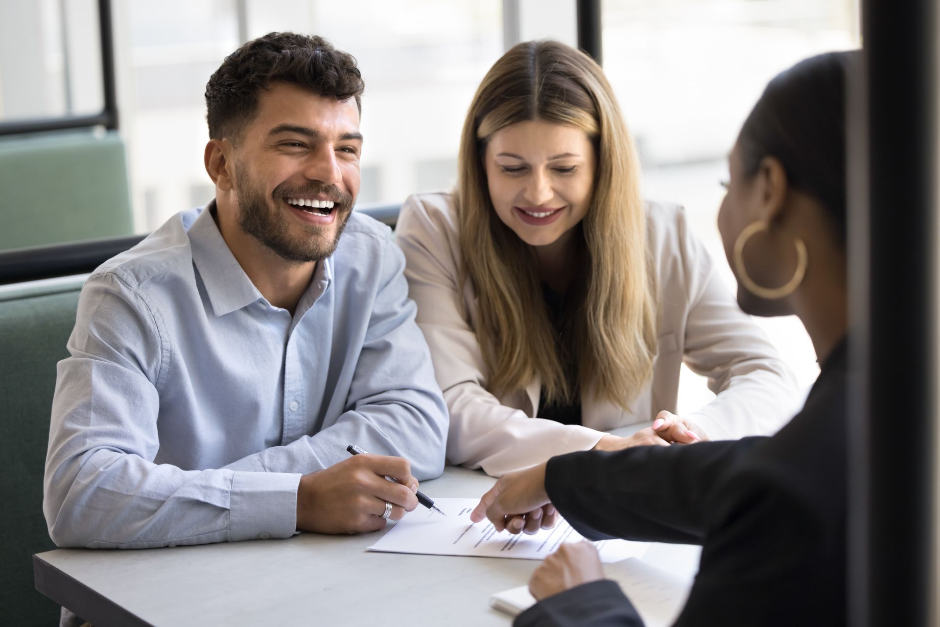 A man and a woman are sitting at a table talking to a woman.