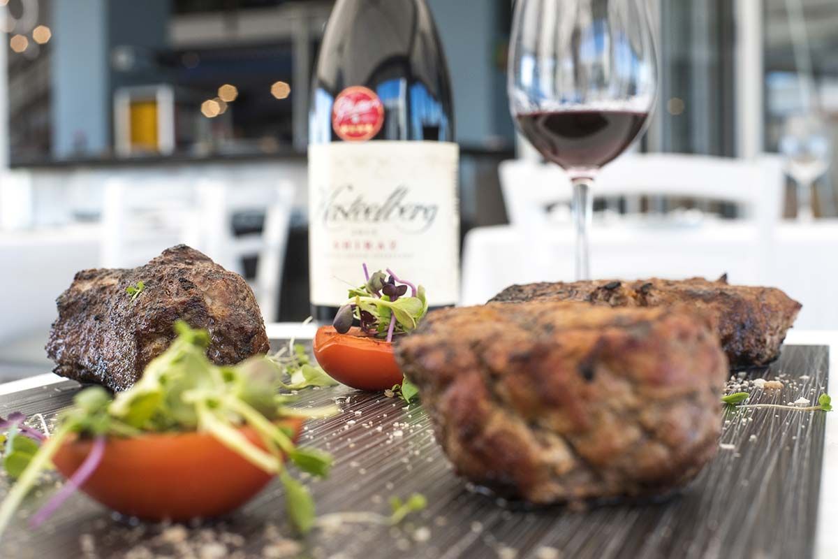 Una bottiglia di vino è appoggiata su un tavolo accanto a un piatto di cibo