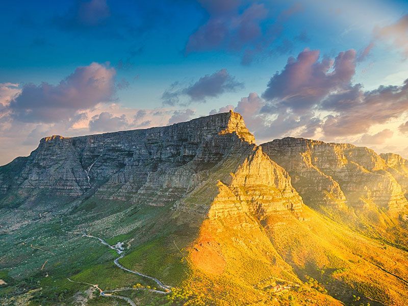 An aerial view of a mountain with a road going through it at sunset.