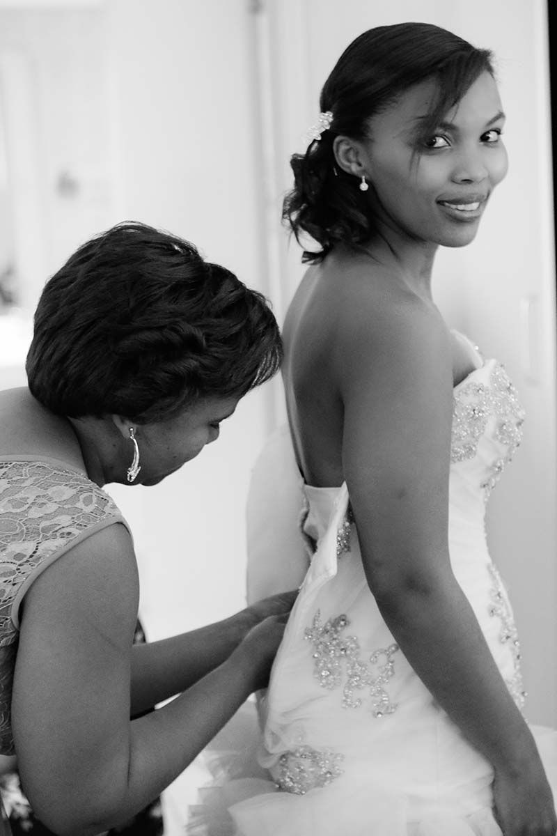 A woman is helping a bride get ready for her wedding