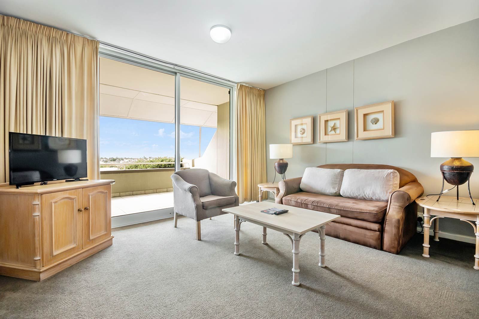 A living room with a couch , chair , coffee table and television.