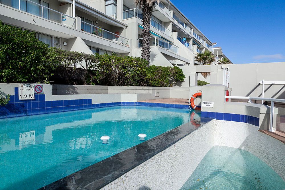 A large swimming pool in front of a building with a sign that says no diving