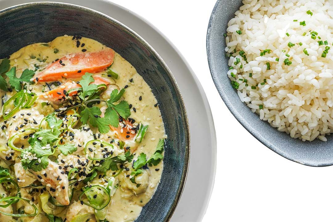 There is a bowl of rice next to a bowl of curry.