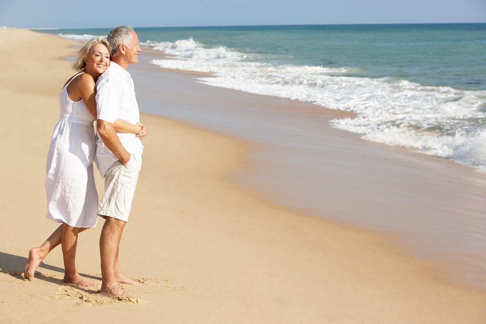 A man and a woman are walking on the beach.