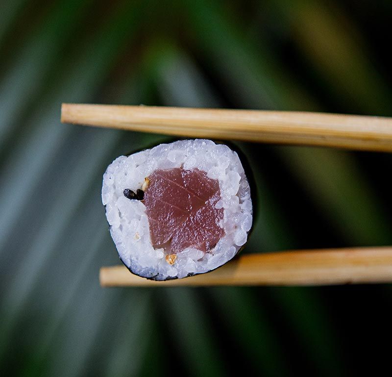 A close up of a sushi roll with chopsticks.