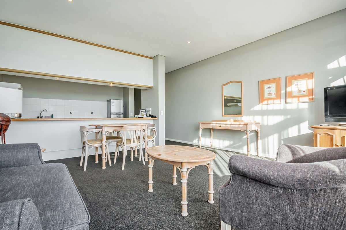 Ein Wohnzimmer mit Couch, Tisch, Stühlen und Fernseher.