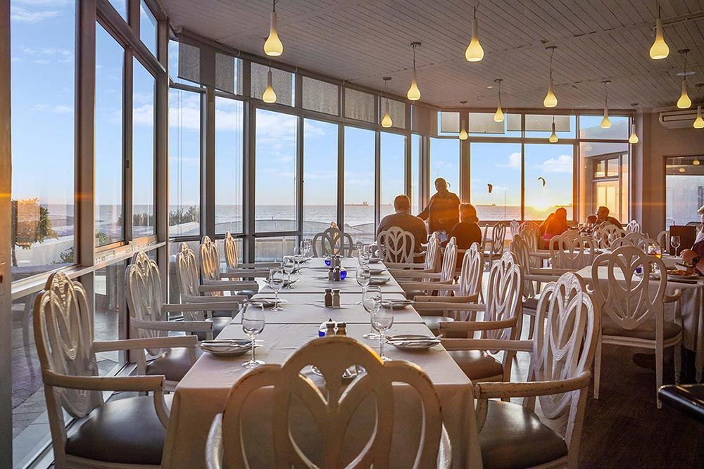 Ein Restaurant mit Tischen und Stühlen und Blick auf das Meer.