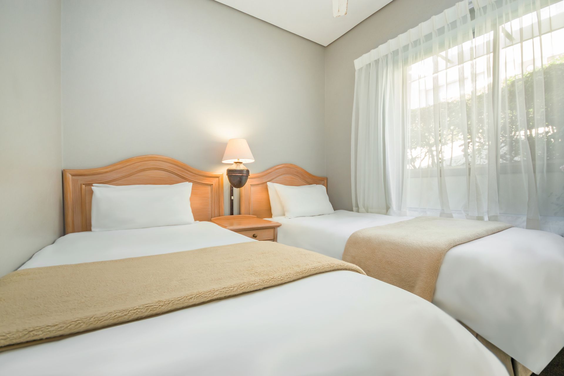 A hotel room with two beds and a window.