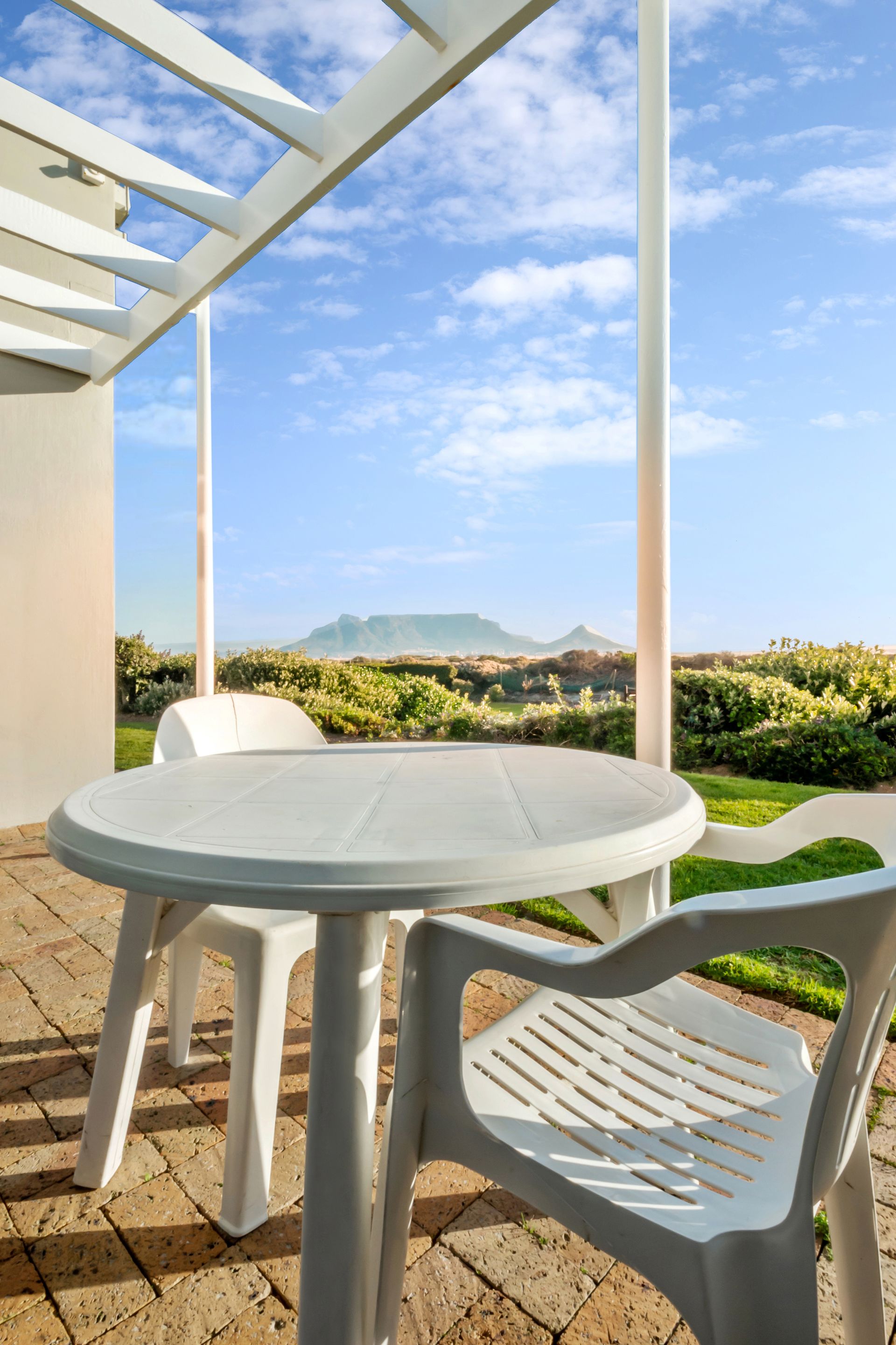 Een tafel en stoelen op een terras met uitzicht op de oceaan