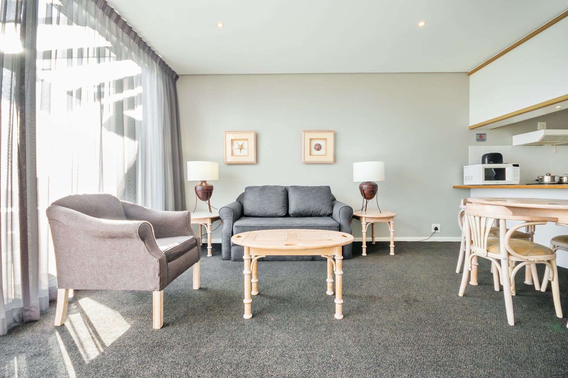 A living room with a couch , chairs , table and lamps.