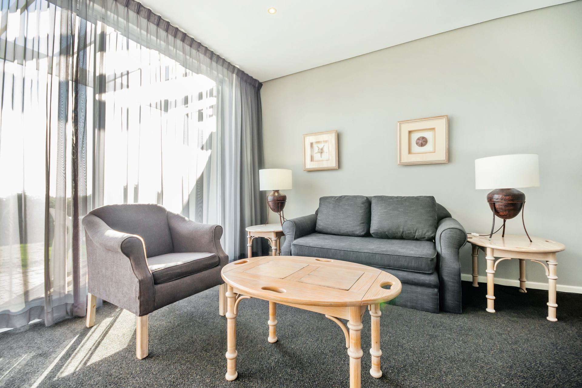 A living room with a couch , chair , table and lamps.