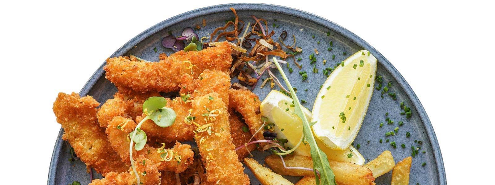 A plate of food with fried chicken and french fries on a white background.