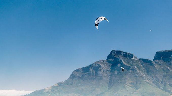 A person is flying a kite over a mountain.