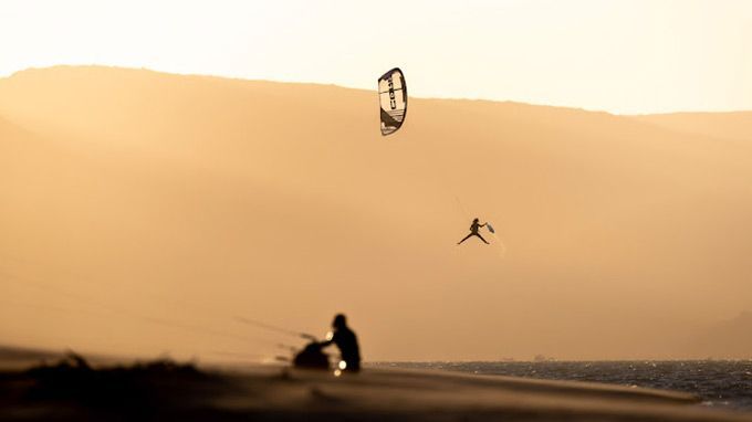 A person is flying a kite over a body of water.