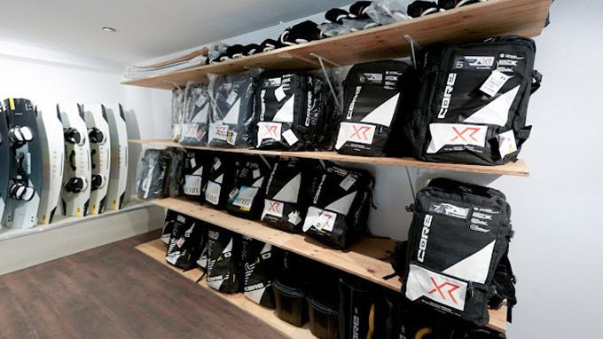 A room filled with lots of backpacks and surfboards.