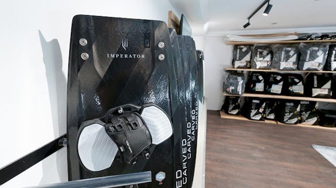 A black and white surfboard is hanging on a wall in a store.