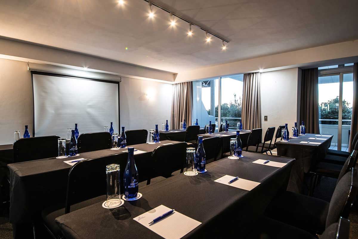 Ein Konferenzraum mit Tischen und Stühlen sowie einer Projektionsleinwand.