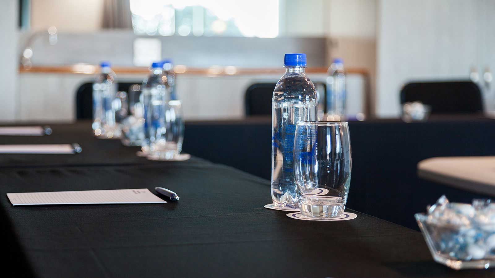 Ein Konferenzraum mit Wasserflaschen und Gläsern auf dem Tisch.