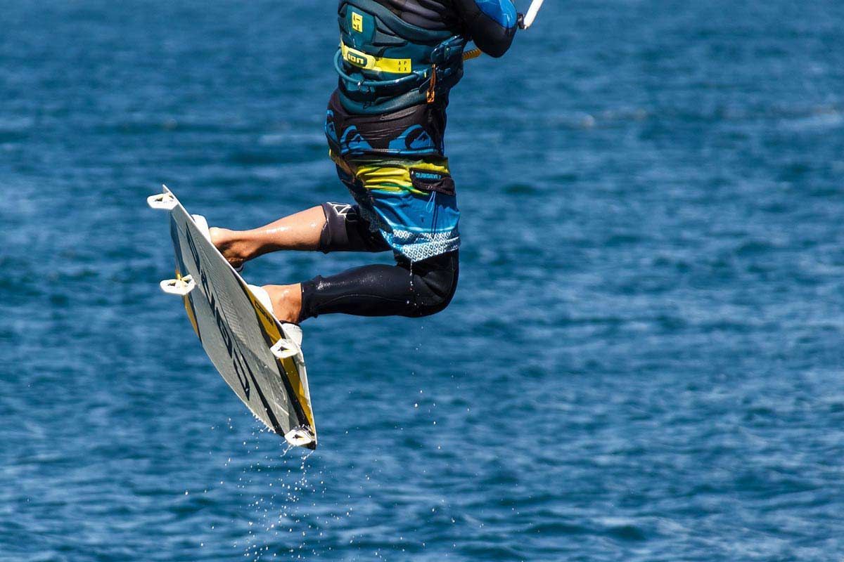Eine Person springt in die Luft, während sie auf einem Surfbrett im Meer reitet.