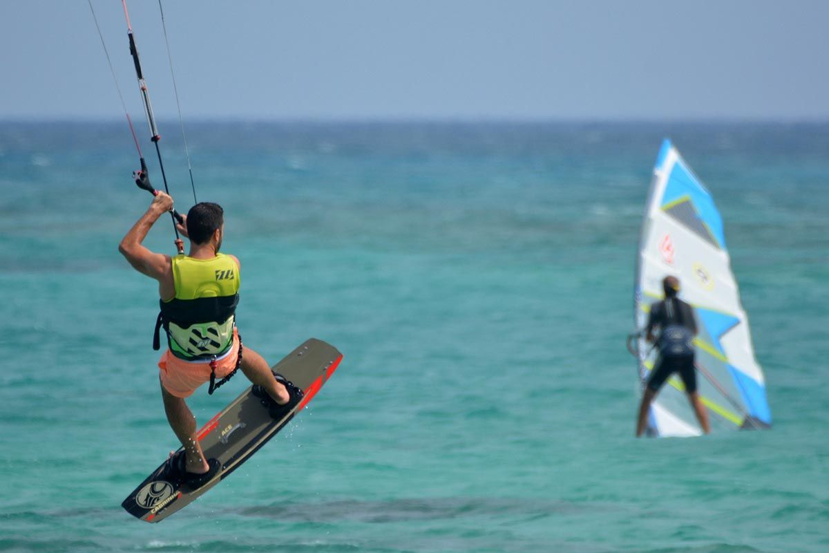 Ein Mann fliegt durch die Luft, während er auf einem Surfbrett im Meer reitet.