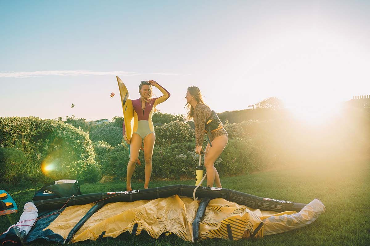 Two women are standing on top of a large kite in a field.