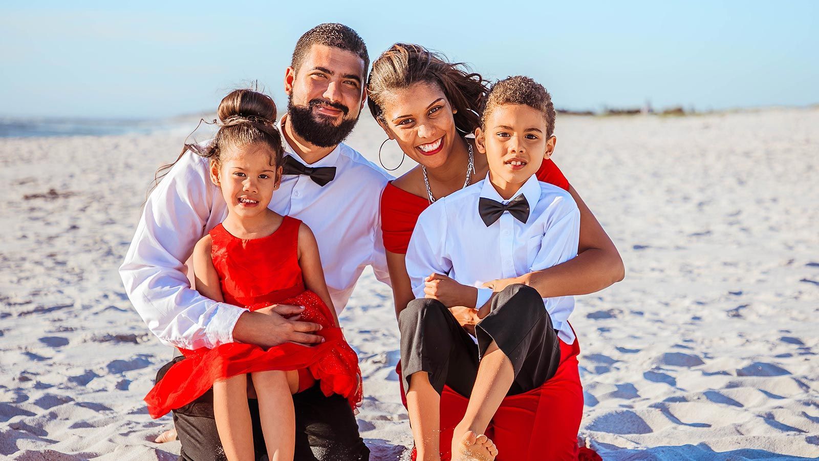 A family is posing for a picture on the beach.