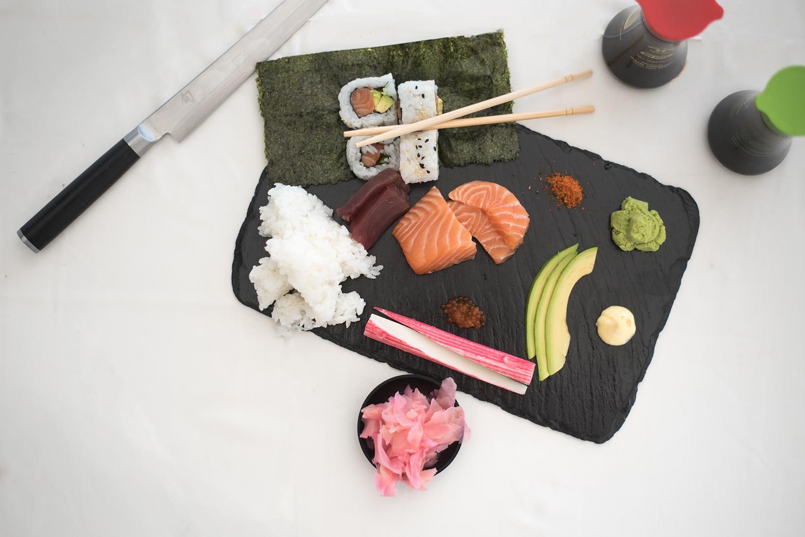 A cutting board filled with sushi and chopsticks on a table.