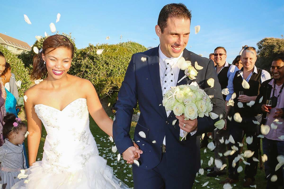 A bride and groom are walking down the aisle surrounded by confetti.