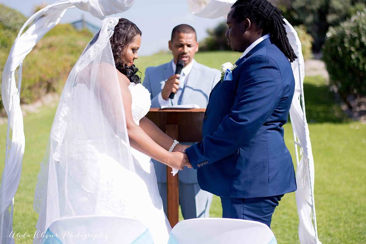 A bride and groom are holding hands during their wedding ceremony.