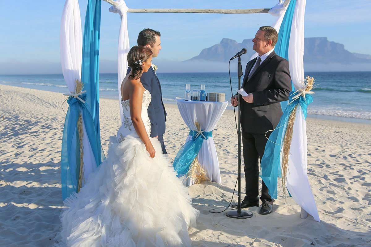 A bride and groom are getting married on the beach.