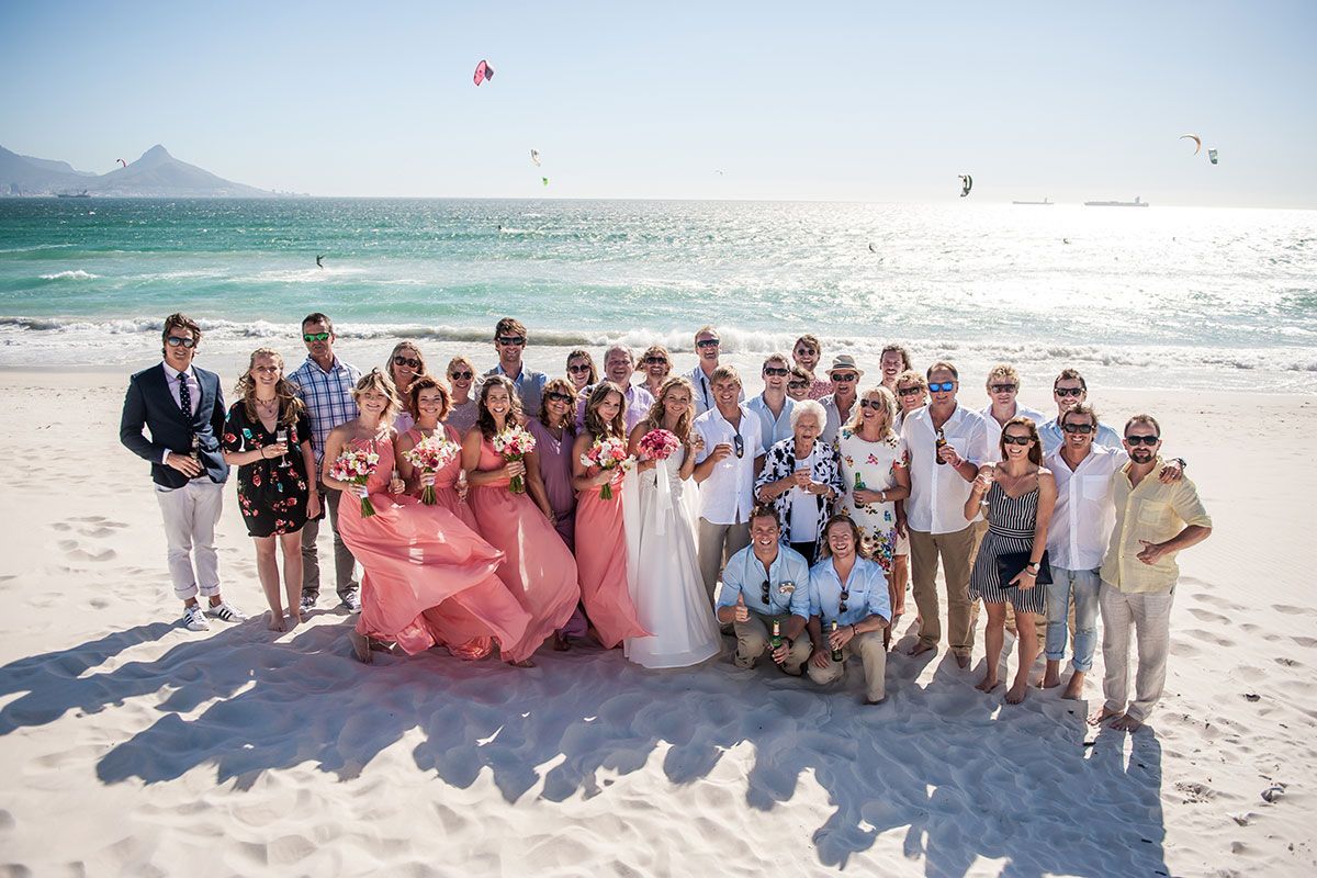 A large group of people are posing for a picture on the beach.