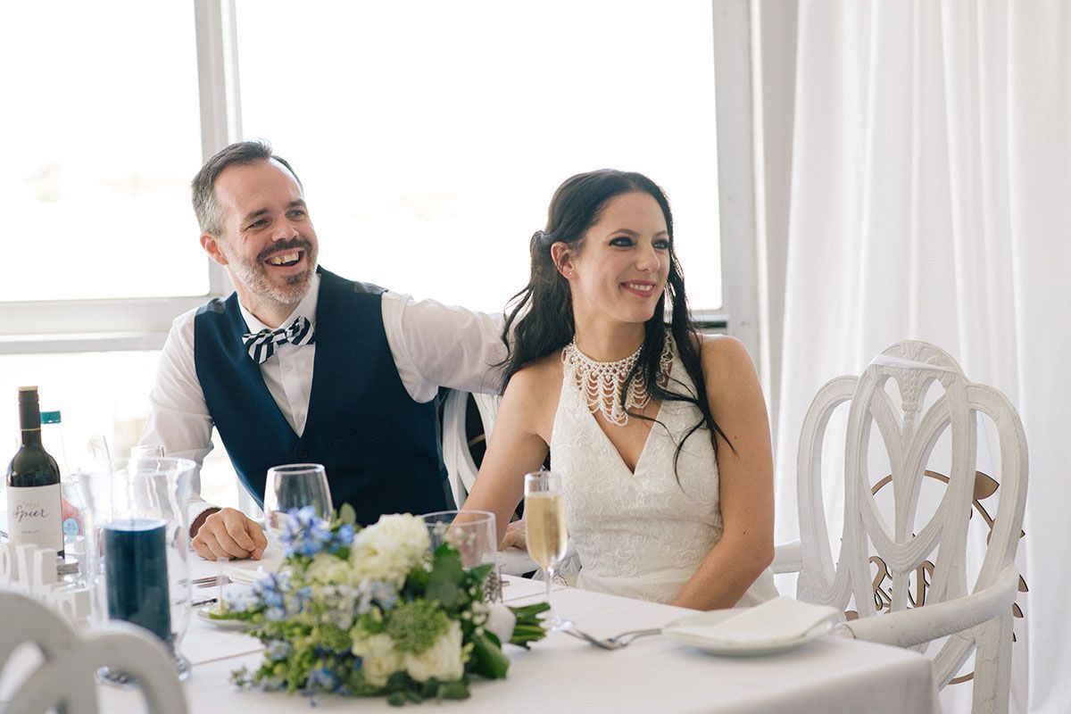 A bride and groom are sitting at a table at a wedding reception.