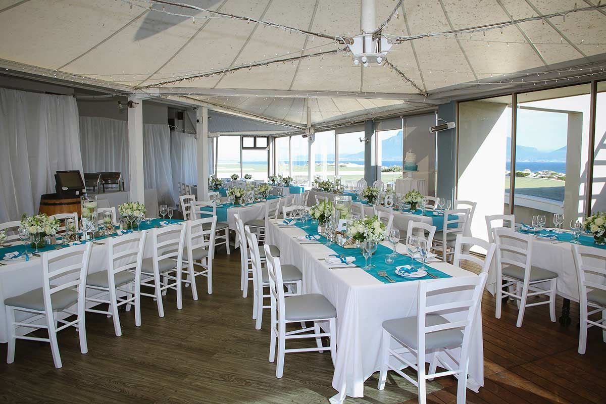 A large room with tables and chairs set up for a wedding reception