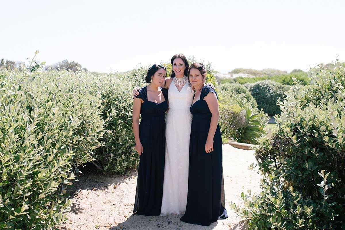 A bride and her two bridesmaids are posing for a picture.